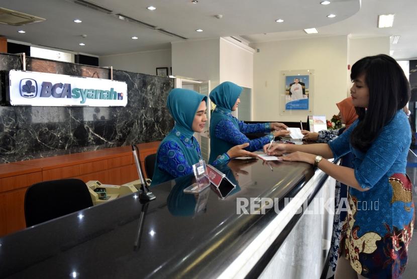 Petugas melayani transaksi nasabah di kantor layanan BCA Syariah, Jakarta, Selasa (6/11).
