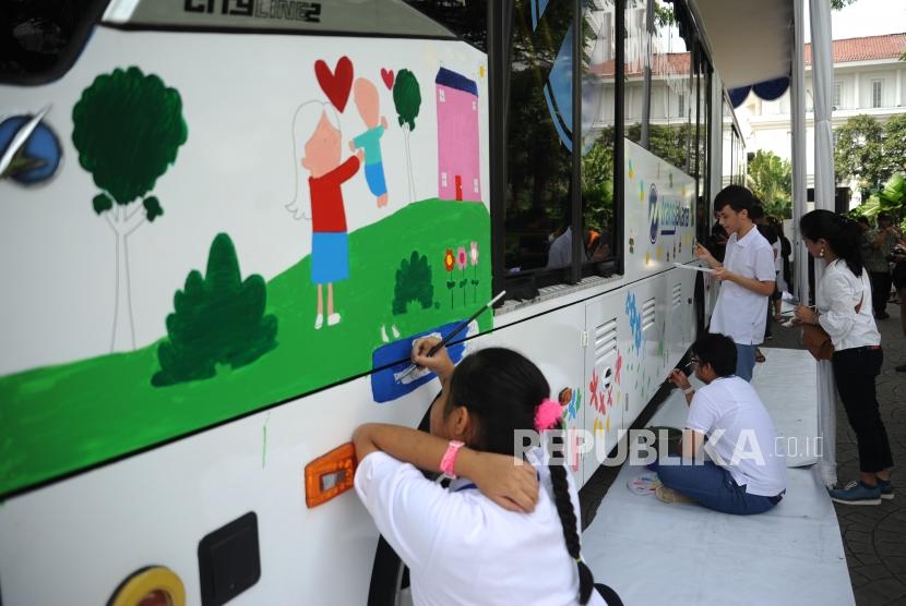 Anak-anak berkebutuhan khusus melukis di badan bus Transjakarta di Balai Kota, Jakarta.