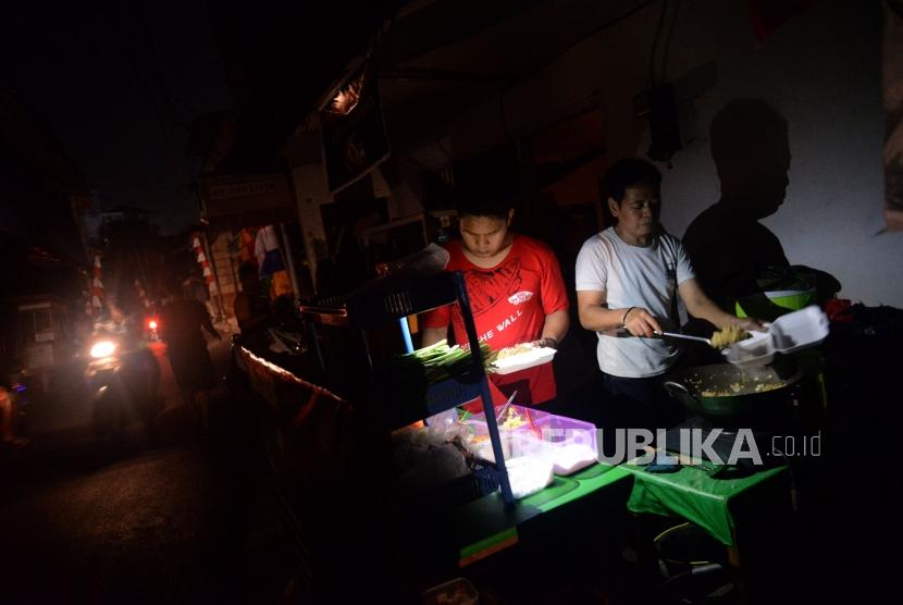 Pedagang melayani pembeli ketika terjadinya pemadaman listik di kawasan pemukiman padat penduduk Karet Tengsin, Jakarta, Ahad (4/8).