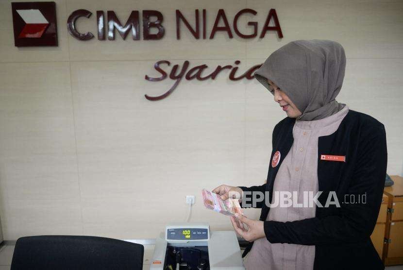 Petugas menghitung uang setoran nasabah di kantor layanan CIMB Niaga Syariah, Jakarta. (ilustrasi)