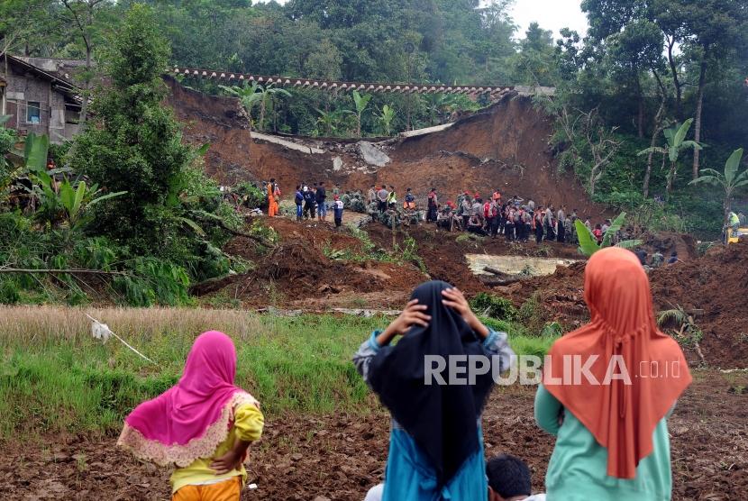 Warga menyaksikan petugas gabungan melakukan evakuasi pencarian korban longsor di Kampung Maseng, Cijeruk, Kabupaten Bogor, Jawa Barat, Selasa (6/2).