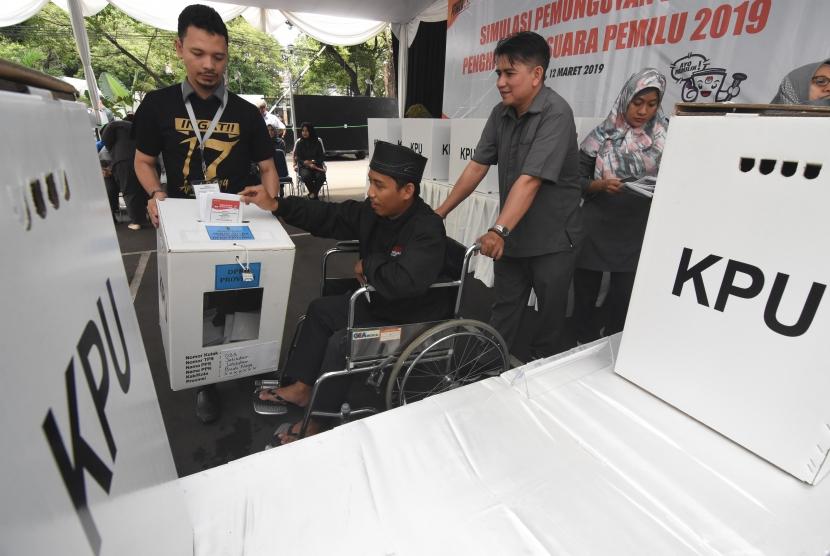 Pemilih disabilitas dibantu pendamping memasukkan suat suara yang telah dicoblos saat menggunakan hak pilihnya pada Simulasi Pemungutan dan Penghitungan Suara Pemilu 2019 di halaman Kantor KPU, Jakarta, Selasa (12/3/2019).