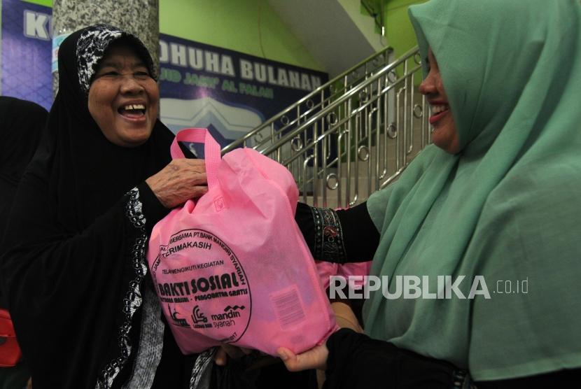 Warga menerima bantuan bakti sosial di Masjid Jami Al Falah, Menteng, Jakarta Pusat, Ahad (17/12).