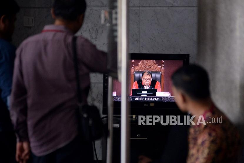 Pengunjung menagmati layar televisi ketika Ketua Majelis Hakim Mahkamah Konstitusi (MK) Arief Hidayat saat memimpin jalannya sidang uji materi Undang-Undang Nomor 7 Tahun 2017 tentang Pemilihan Umum (UU Pemilu) dengan agenda pembacaan putusan di Mahkamah Konstitusi, Jakarta, Kamis (11/1).