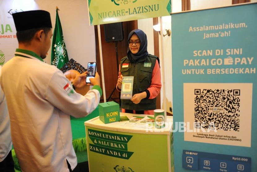 ZIS Digital Nahdliyin memindai QR Barcode untuk pembayaran zakat, infak dan sedekah secara non tunai melalui Go-Pay dalam peluncuran Kerjasama Strategis Pemberdayaan Ekonomi Umat berbasis Digital antara Gojek, Go-Pay dengan NU Care LazisNU di Jakarta, Selasa (16/7).