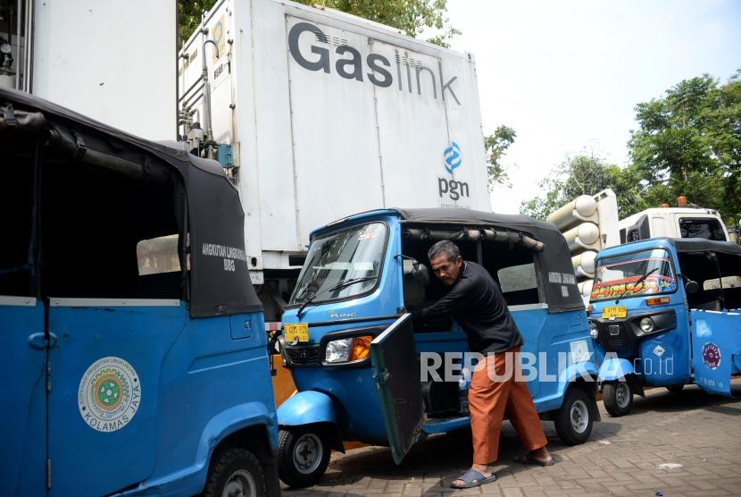 Pengemudi mendorong bajaj miliknya ketika mengantri saat mengisi BBG di Mobile Refueling Unit (MRU) milik PT Perusahaan Gas Negara (PGN) di Kawasan Monas, Jakarta, Ahad (21/10).