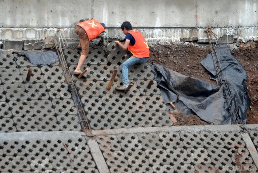 Pekerja menyelesaikan proyek normalisasi Sungai Ciliwung di Bukit Duri, Jakarta.