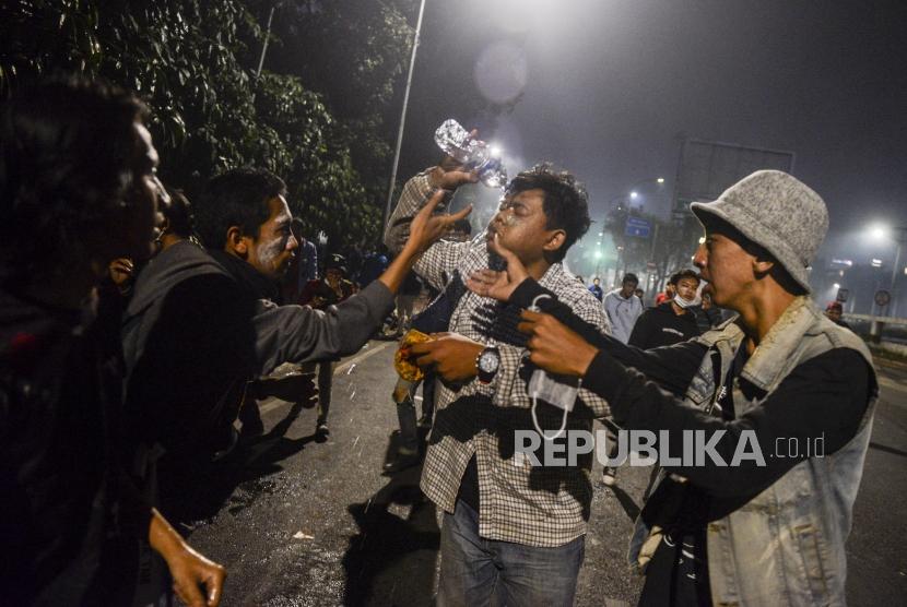 Sejumlah mahasiswa membasuhkan air saat ditembakan gas air mata di depan Gedung DPR, Jakarta, Selasa (24/9).