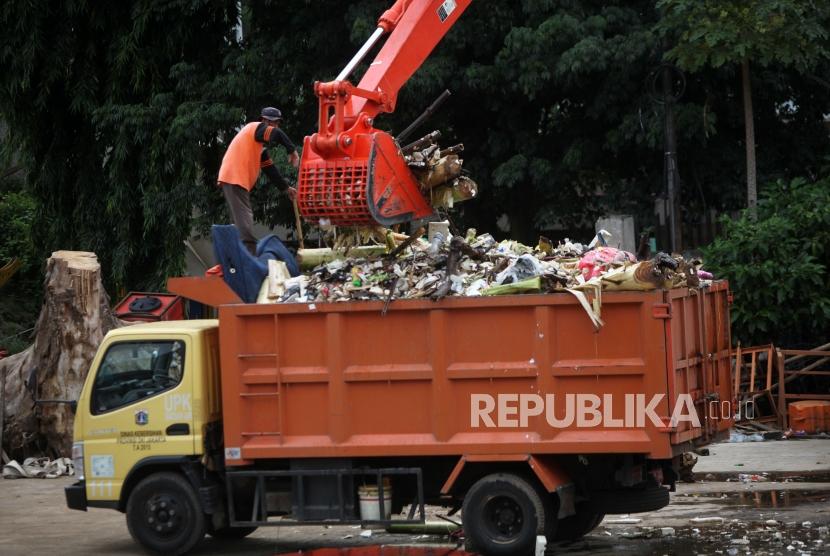 Petugas menggunakan alat berat mengangkut sampah di Pintu Air Manggarai, Jakarta, Rabu (13/12).