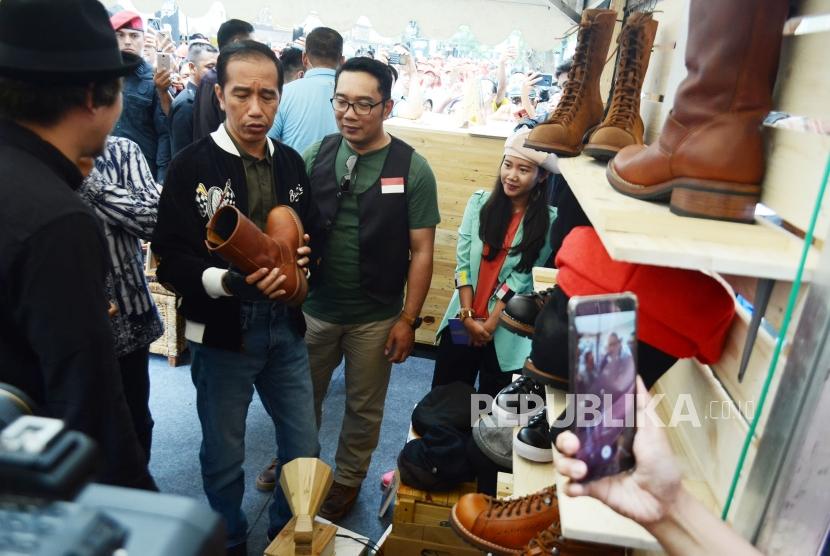 Presiden RI Joko Widodo (Jokowi) mengamati produk sepatu kulit pada pameran Komunitas Kreatif, di Jalan Braga, Kota Bandung, Ahad (11/11).