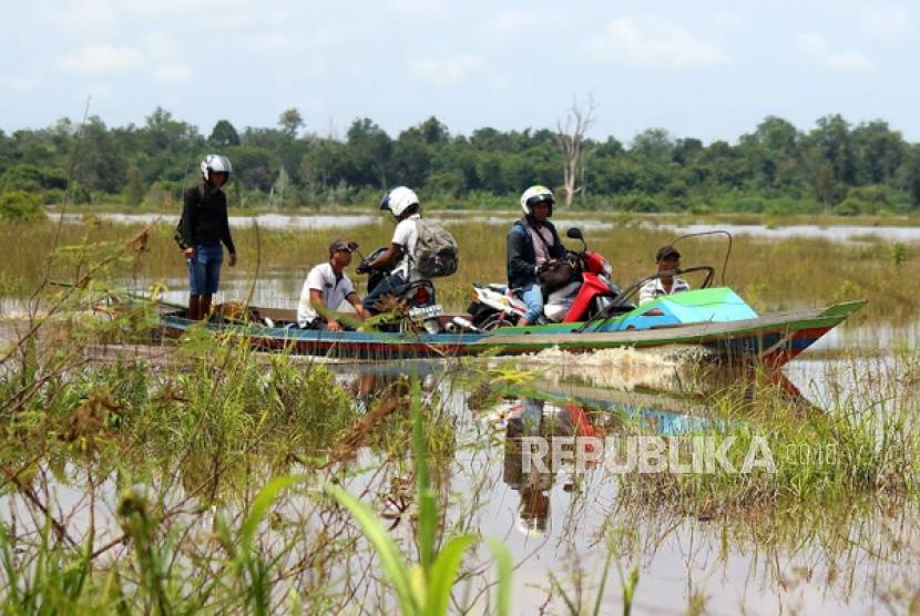 Warga menggunakan perahu melewati lahan persawahan yang tergenang banjir di Kalteng. (Ilustrasi)
