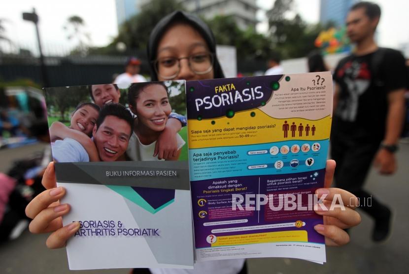 Mahasiswa dari FKUI memperlihatkan buku dan brosur saat menggelar kampanye tentang penyakit Psoriasis saat Hari Bebas Kendaraan Bermotor atau car free day di kawasan Bundaran HI, Jakarta, Ahad (4/11).