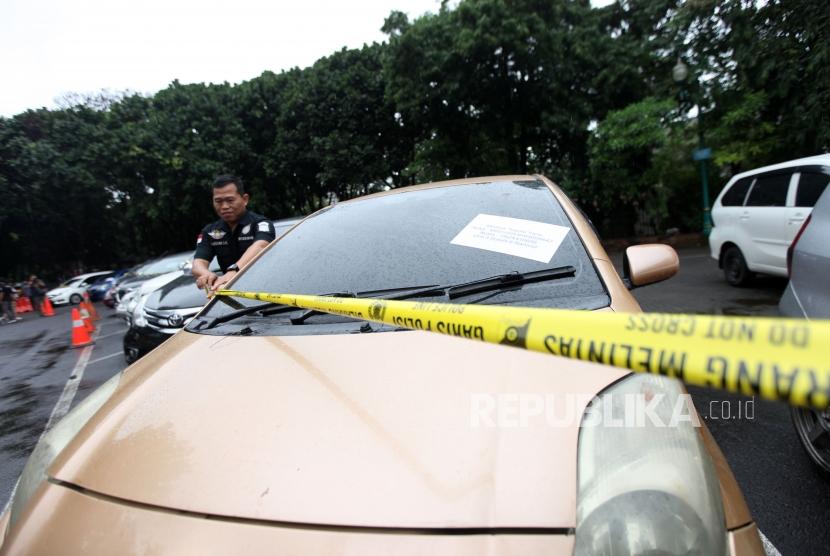 Petugas polisi memasang garis polisi barang bukti kendaraan mobil saat rilis kasus kendaraan bermotor di Polda Metro Jaya, Jakarta, Ahad (26/11).