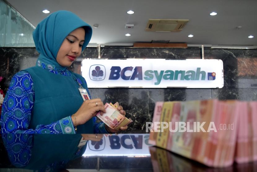 Petugas menghitung uang nasabah ketika transaksi di kantor layanan BCA Syariah. ilustrasi