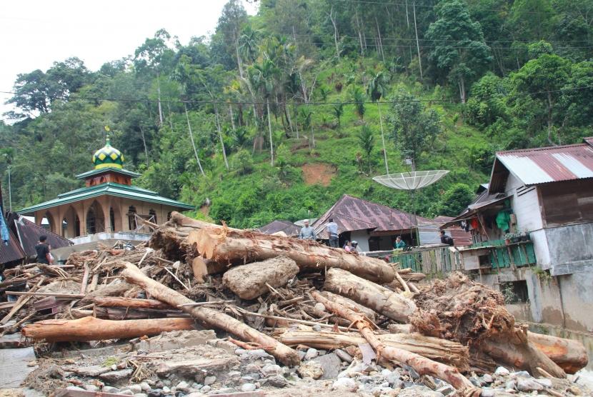 Beberapa warga berada di antara kayu yang terbawa arus sungai pascabanjir bandang (ilustrasi)