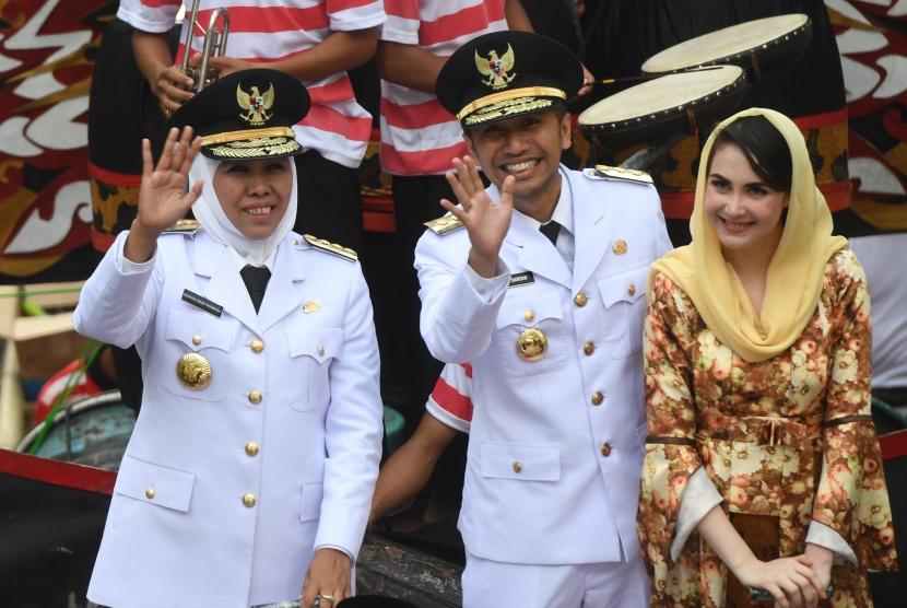 Gubernur Jawa Timur Khofifah Indar Parawansa (kiri) bersama Wakil Gubernur Jawa Timur Emil Elestianto Dardak (tengah) dan istrinya Arumi Bacshin (kanan) menyapa warga ketika diarak menuju Grahadi, Surabaya, Jawa Timur.