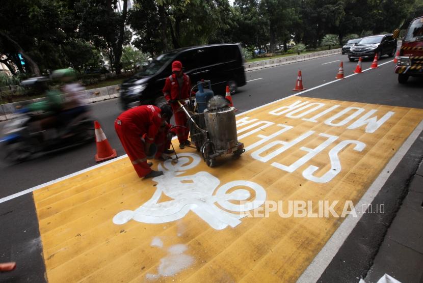 Pekerja mengecat jalur kuning khusus sepeda motor di Kawasan Jalan Merdeka Barat, Jakarta, Rabu (17/1).