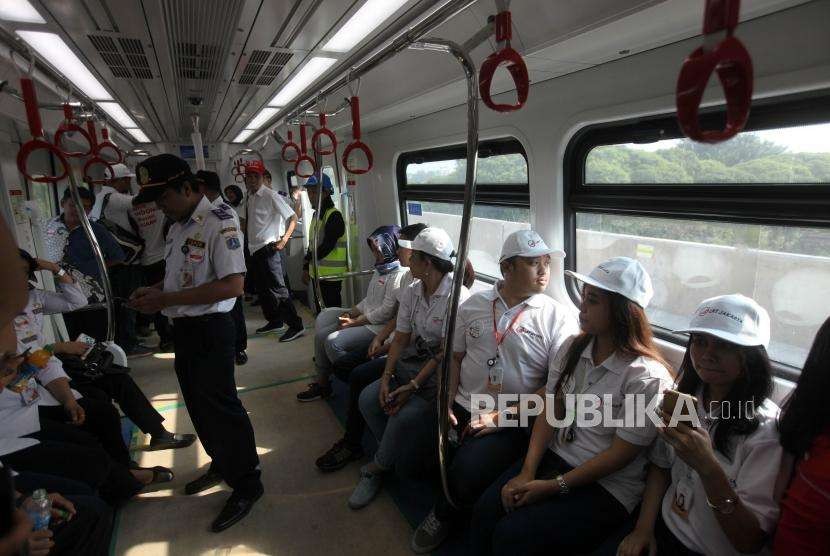 Para petugas menaiki kereta light rail transit (LRT) saat uji coba di Stasiun LRT Velodrome, Jakarta, Rabu (15/8).