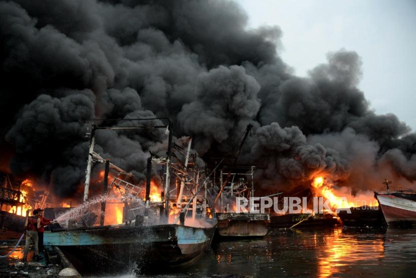 Sejumlah petugas pemadam kebakaran dibantu warga berusaha memadamkan kapal yang terbakar di Pelabuhan Muara Baru, Jakarta, Sabtu (23/2).