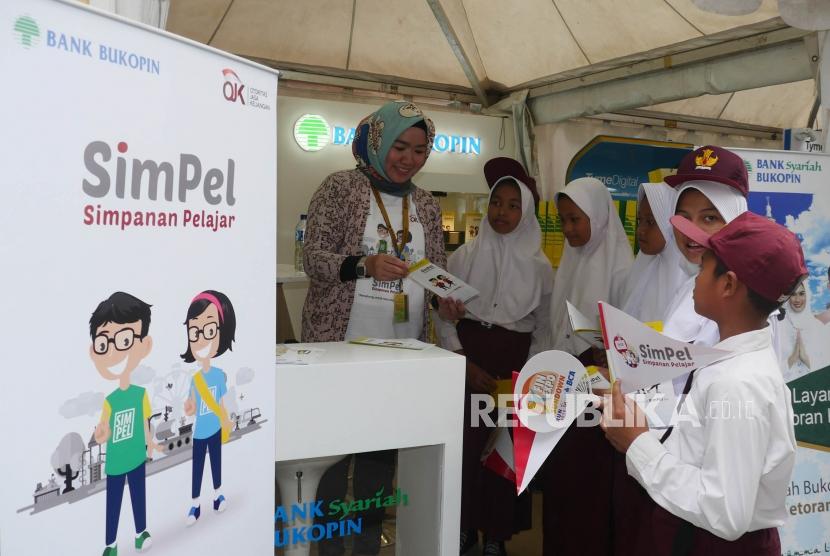 Seorang petugas bank menjelaskan produk tabungan SimPel (Simpanan Pelajar) kepada sejumlah siswa yang mengunjungi booth bank pada rangkaian acara “Financial Institutions” 