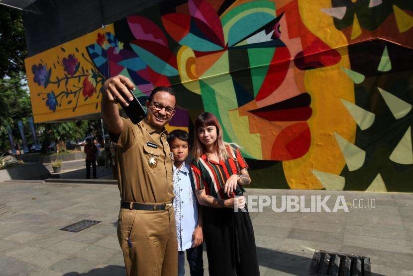 Gubernur DKI Jakarta Anies Baswedan bersama Seniman Kolombia Ledania berfoto selfie saat meninjau mural di Taman Ismail Marzuki, Jakarta, Senin (10/9).