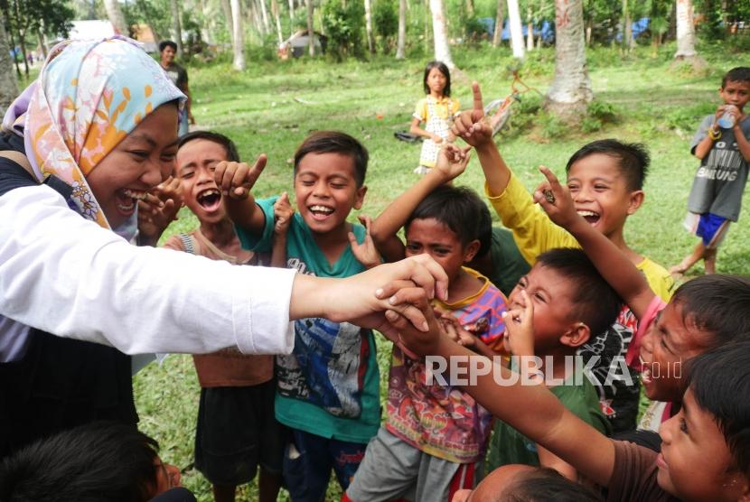 Seorang relawan ACT bermain dengan anak-anak di desa Lompio Kabupaten Sirenja, Donggala Sulawesi Tengah, Ahad (14/10).