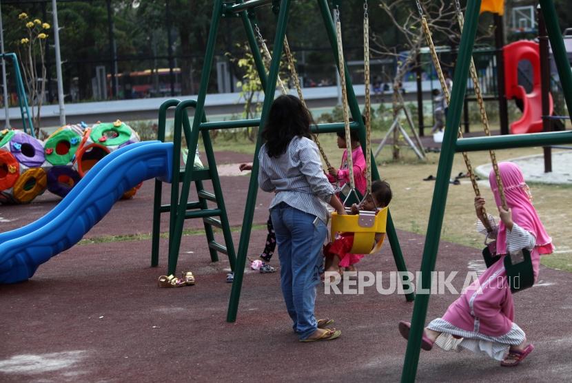 Seorang anak bermain didampingi orang tuanya di area Taman Anak Lapangan Banteng, Jakarta, Kamis (12/7).