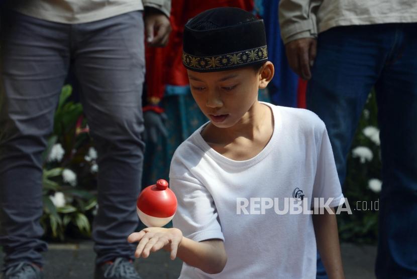 Anak-anak bermain gangsing pada acara Festival Permainan Tradisional Anak Betawi di Hutan Kota Srengseng, Jakarta, Sabtu (3/8).