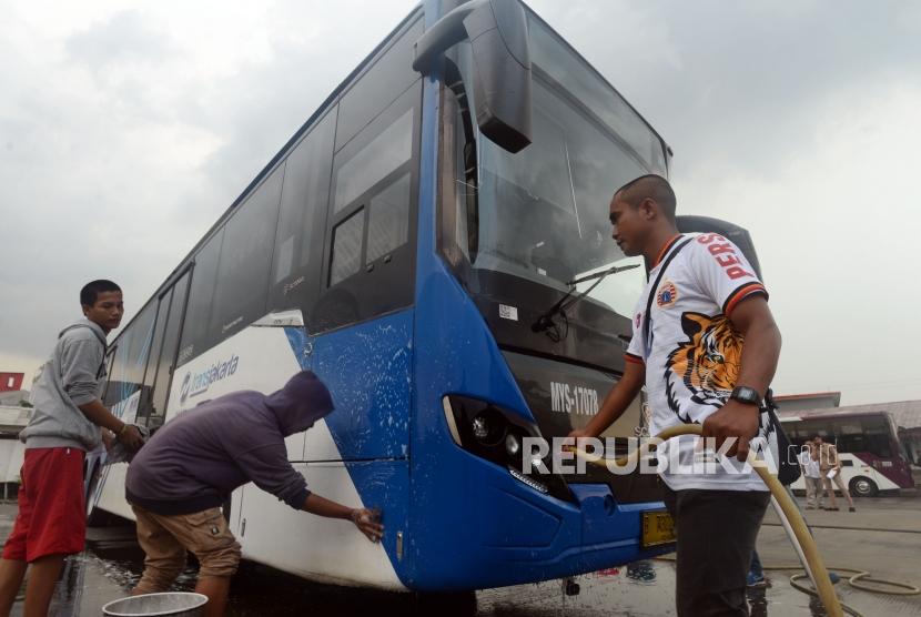 Sejumlah suporter Persija membersihkan bus Transjakarta di Kantor PT Transjakarta, Cawang, Jakarta, Kamis (13/12).