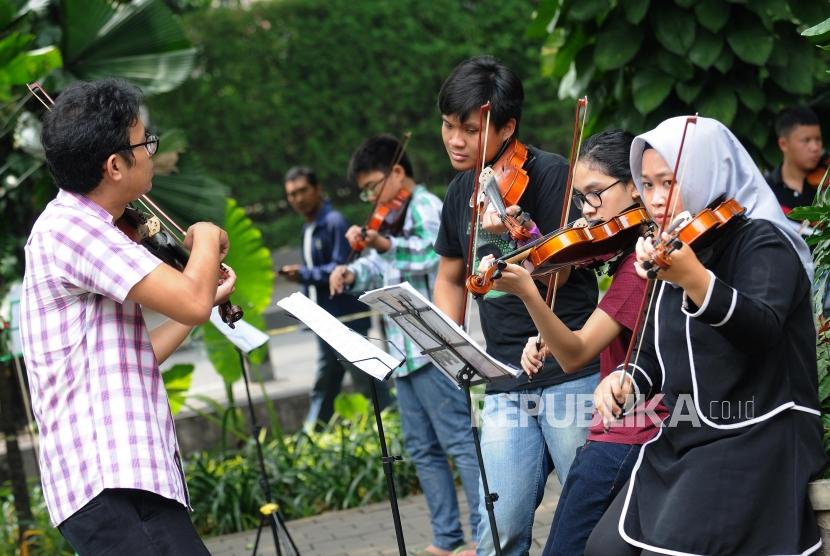 Anak-anak belajar memainkan alat musik biola di Taman Suropati, Menteng, Jakarta, Ahad (15/4).