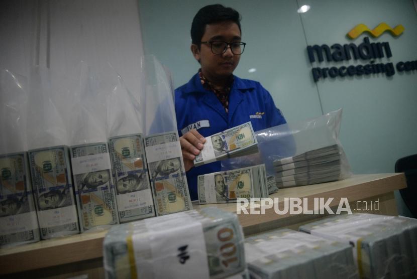 Karyawan menghitung tumpukan uang dolar Amerika Serikat di Cash Center Bank Mandiri, Jakarta, Senin (23/7).