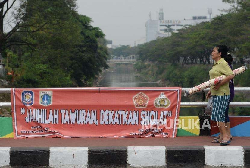 Warga melintas di dekat spanduk bertuliskan himbauan stop tawuran di Kawasan Pasar Rumput, Jakarta, Rabu (29/8).