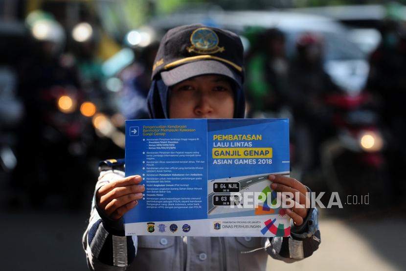 Petugas Dinas Perhubungan memperlihatkan brosur sosialisasi uji coba perluasan ganjil genap di kawasan Pancoran, Jakarta Selatan, Senin (2/7).