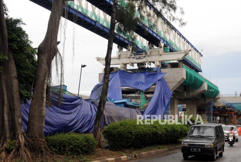 Kendaraan melintas di samping konstruksi proyek Light Rapid Transit (LRT) yang roboh di Jalan Raya Kayu Putih, Pulogadung, Jakarta Timur, Senin (22/1).