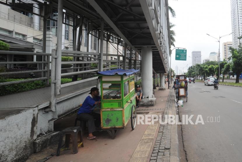 Pedagang berjualan di trotoar di kawasan Jalan Jendral Sudirman, Jakarta Pusat, Ahad (17/12).