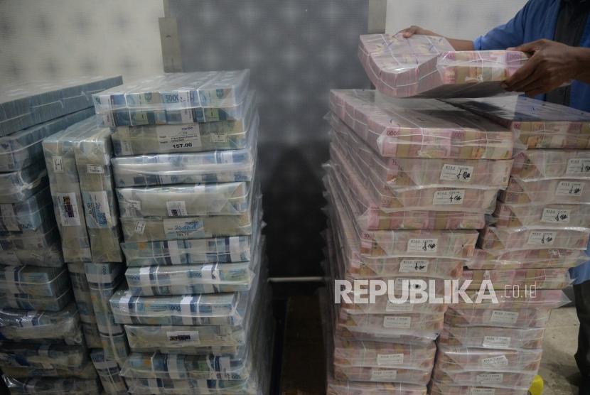 Petugas menata tumpukan uang rupiah di Cash Center Bank Mandiri,Jakarta, Senin (23/7).