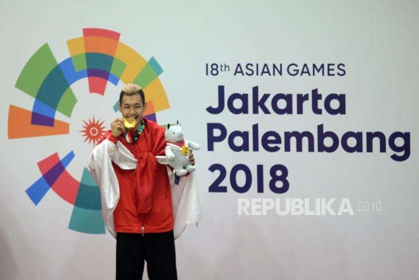 Pesilat Indonesia Hanifan Yudani Kusumah menggigit medali emas usai mengalahkan pilat Vietnam Thai Linh Nguyen pada cabang olahraga silat Asian Games 2018 kategori kelas 55-60 kilogram  di Padepokan Pencak Silat TMII, Jakarta, Rabu (29/8).