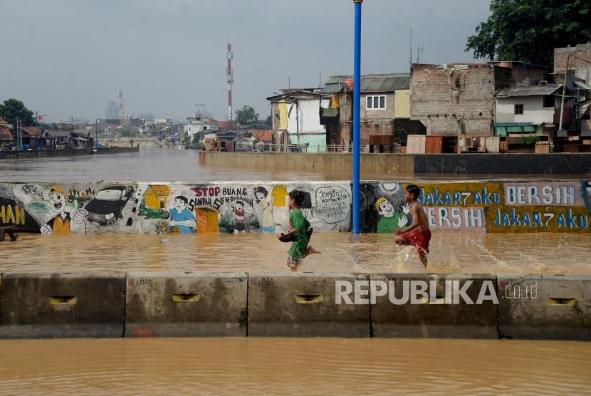 Children play amid the floods that hit the West Jatinegara road, Jakarta, Tuesday (Feb 6).