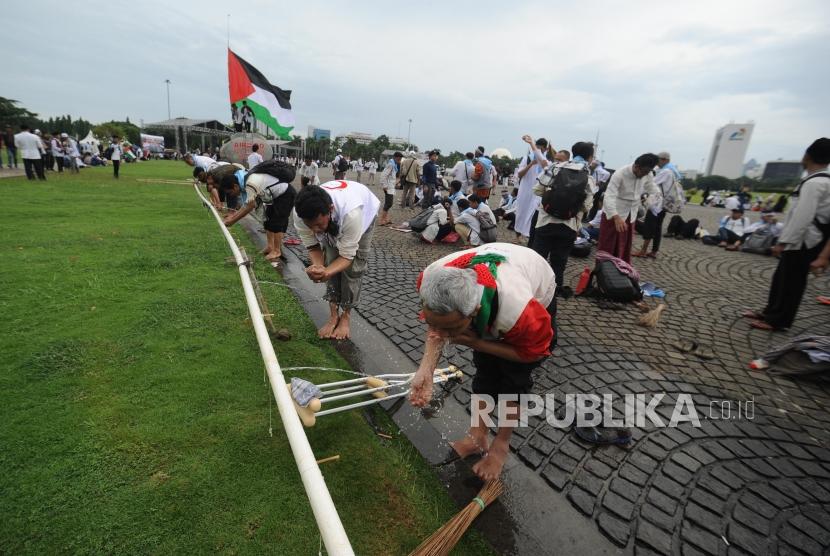 Peserta aksi solidaritas Palestina sedang berwudhu untuk persiapan menunaikan ibadah shalat seusai melakukan aksi solidaritas palestina di Monumen Nasional, Jakarta,Ahad (17/12).