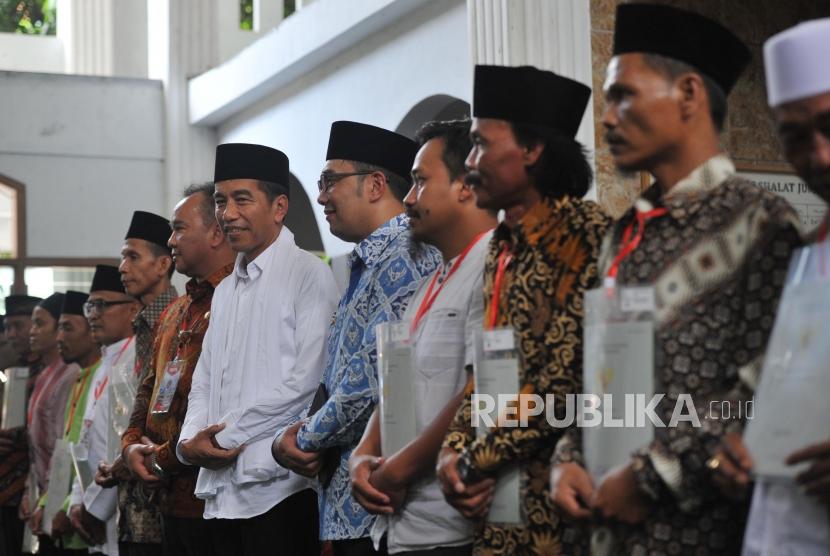 Presiden Joko Widodo (kiri) berfoto bersama seusia memberikan sertifikat tanah wakaf ke warga saat berkunjung ke Pondok Pesantren Al-Ittihad, Cianjur, Jumat (8/2).