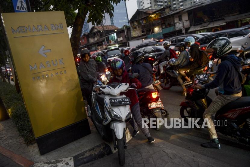 Pengendara motor mendorong motornya melalui trotoar saat terjadi kemacetan di kawasan Pejompongan, Jakarta, Selasa (24/9).