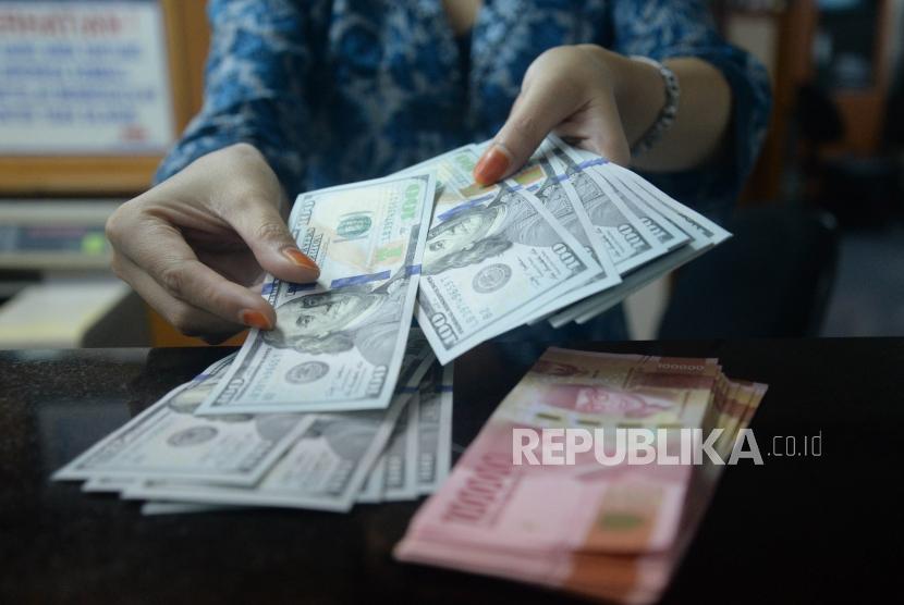 Petugas menghitung pecahan dolar Amerika Serikat di salah satu gerai penukaran mata uang asing di Jakarta. ilustrasi
