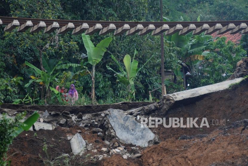 Warga melihat kondisi jalur kereta api jurusan Sukabumi-Bogor yang menggantung akibat pondasi longsor di Kampung Maseng, Cijeruk, Kabupaten Bogor, Jawa Barat, Selasa (6/2).