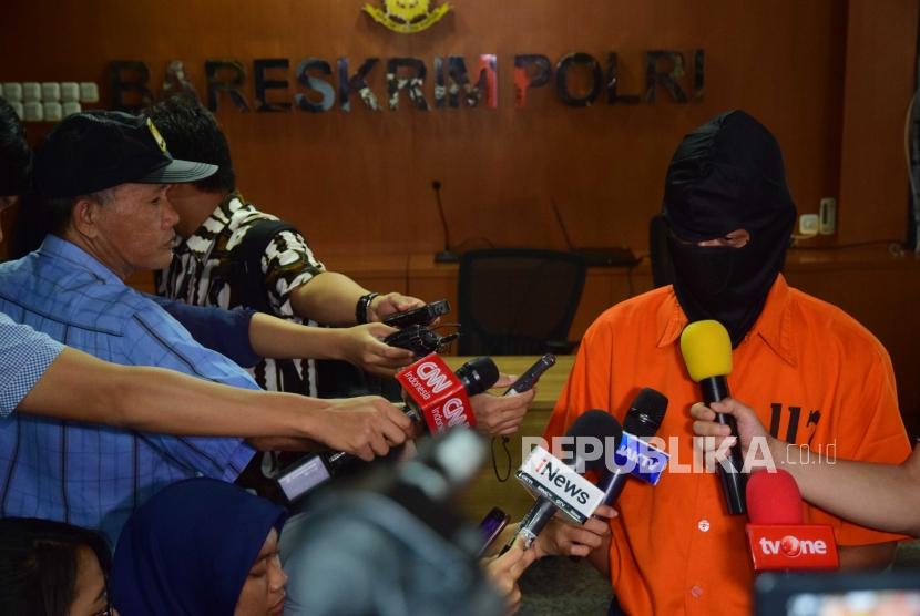 Tersangka deface website Bawaslu memberikan keterangan kepada media  saat dihadirkan dalam konfrensi pers di  Bareskrim Polri, Jakarta, Jumat (6/7).