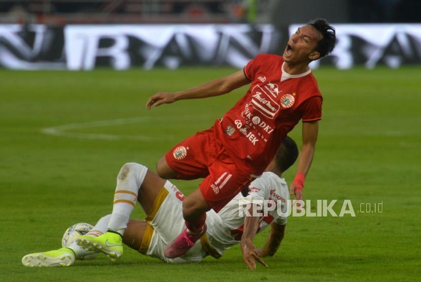 Pemain Persija Jakarta Novri Setiawan terjatuh saat berebut bola dengan pemain PSM Makassar dalam laga lanjutan Liga 1 di Stadion Gelora Bung Karno, Senayan, Jakarta, Rabu (28/8).