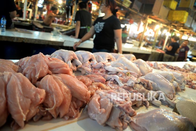 Pedagang melayani pembeli daging ayam potong di pasar.