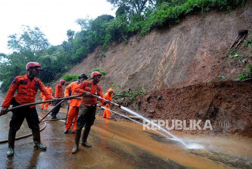 Petugas gabungan menyiram air saat evakuasi longsor di Jalur Utama Puncak, Bogor, Jawa Barat, Senin (5/2).