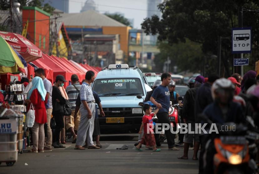 Warga bejalan didepan kendaraan angkutan kota (angkot) jurusan Tanah Abang yang melintas di Jalan Jatibaru, Tanah Abang, Jakarta, Ahad (4/2).