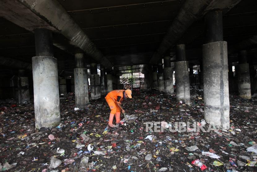 Petugas PPSU membersihkan sampah yang menumpuk di bawah Jalan Tol Ir. Wiyoto Wiyono Tanjung Priok, Jakarta Utara, Rabu (18/4).