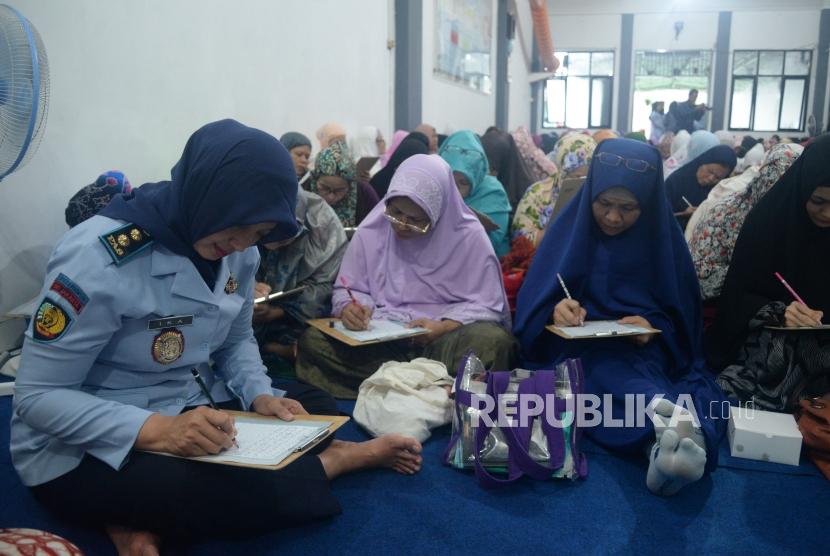 Kepala Lapas Pondok Bambu Ika Yusanti (Kiri) bersama sejumlah warga binaan mengikuti acara menghatamkan Al-Quran tulis dengan metode Follow The Line di Aula Lembaga Pemasyarakatan Perempuan Kelas II A, Pondok Bambu, Jakarta, Kamis (15/2).